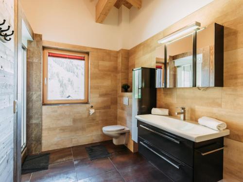 a bathroom with a sink and a toilet and a mirror at Bernkogel Penthouse in Rauris