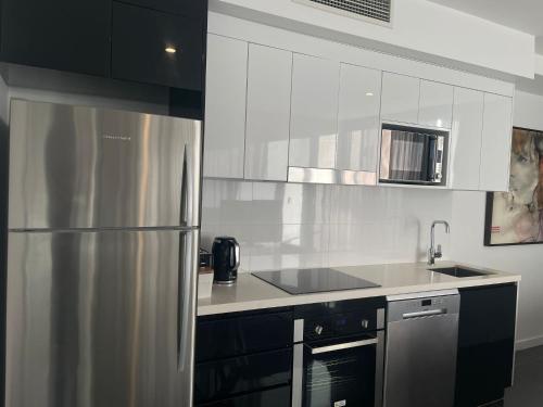 a kitchen with a stainless steel refrigerator and cabinets at High Street Apartments Toowong in Brisbane