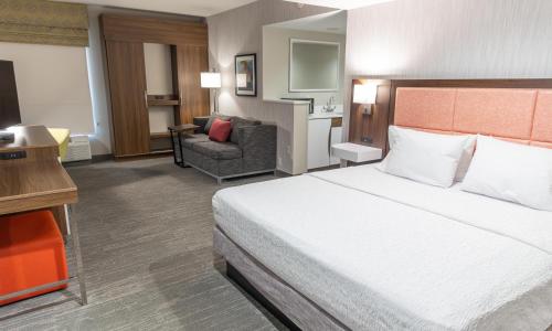 a hotel room with a large bed and a chair at Hampton Inn Williamsport in Williamsport