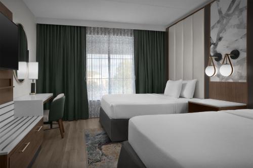 a hotel room with two beds and a desk at Embassy Suites by Hilton Jackson North Ridgeland in Ridgeland