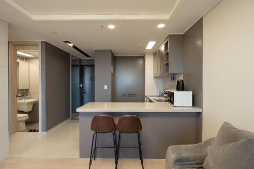 a kitchen with two stools and a counter in a room at Hotel The Blue Terra in Sokcho