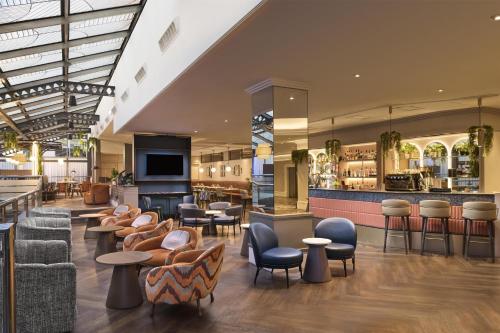 a lobby with chairs and tables and a bar at Hilton Leeds City in Leeds