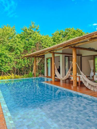 a villa with a swimming pool and hammocks at Orixás Residence -Casa Yemanja Morro in Cairu