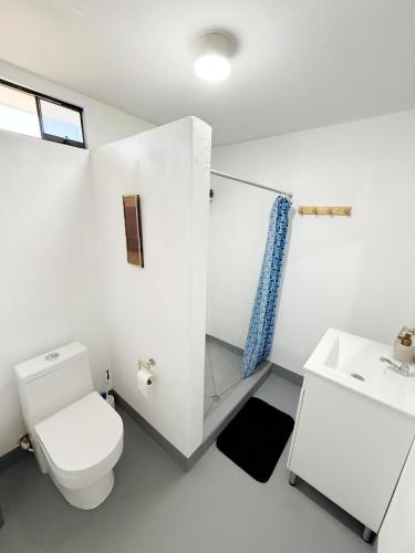 a white bathroom with a toilet and a sink at Surf & Sand Lobitos in Lobitos