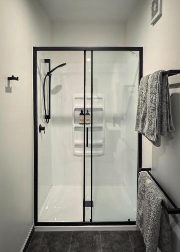 a shower with a glass door in a bathroom at Guesthouse on Gardiners in Christchurch