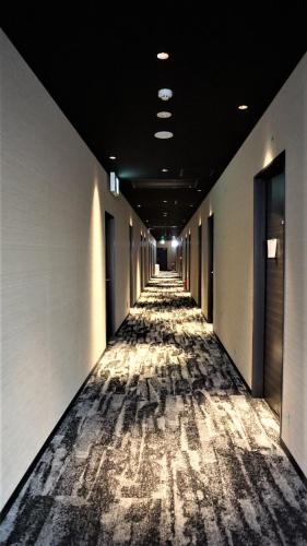a hallway of an office building with a carpeted floor at Astil Hotel Shinosaka Precious in Osaka