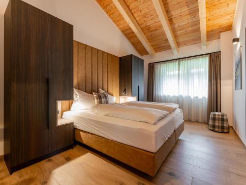 a bedroom with a large bed with a wooden wall at Grebenzen Lodge Edelblick in Sankt Lambrecht