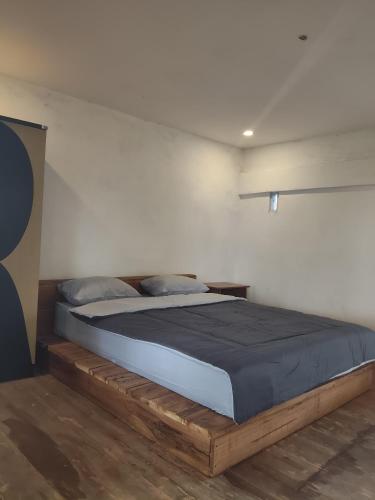 a bedroom with a bed with a wooden bed frame at Benang Kelambu Cottage in Praya