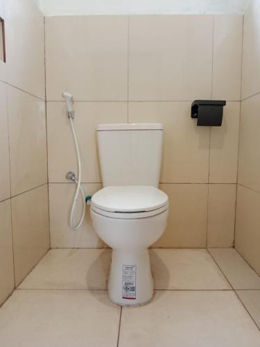 a white toilet in a bathroom with a shower at Benang Kelambu Cottage in Praya