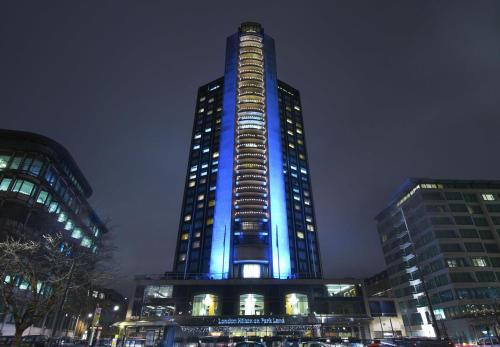 a tall building with blue lights on it at night at London Hilton on Park Lane in London