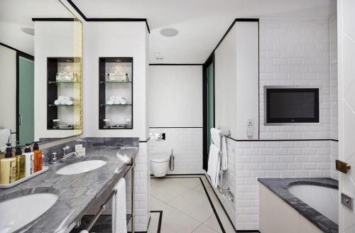 a bathroom with two sinks and a flat screen tv at The Waldorf Hilton in London