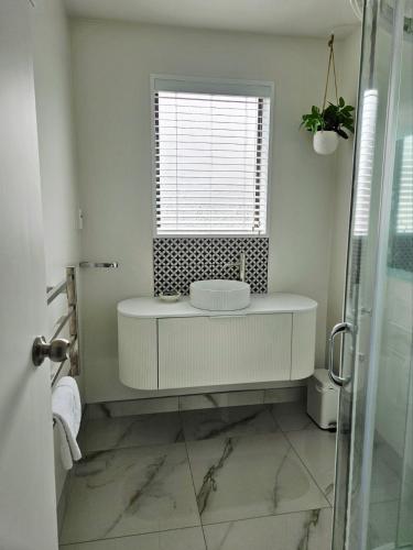 a white bathroom with a sink and a window at 27 Alpine Avenue in Hanmer Springs