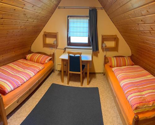 two beds in a room with a desk and a table at Wohnung mit Balkon im Schwarzwald in Seebach