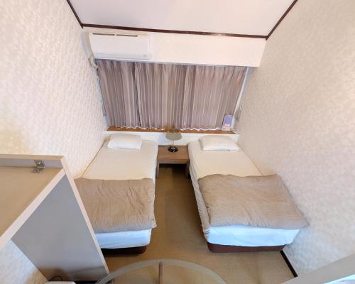 a small room with two beds and a window at Nikko TEN Stay in Nikko
