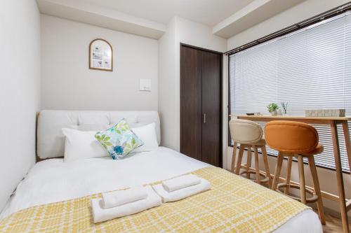 a bedroom with a bed and a table and chairs at Hopetree NambaImamiya in Osaka