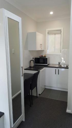 a kitchen with white cabinets and a microwave at John Oxley Motel in Port Macquarie