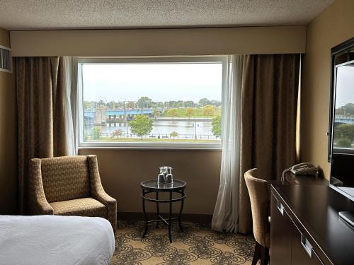 a hotel room with a bed and a window and a chair at DoubleTree by Hilton Bay City - Riverfront in Bay City