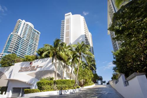 a building with palm trees in front of tall buildings at DoubleTree by Hilton Ocean Point Resort - North Miami Beach in Miami Beach