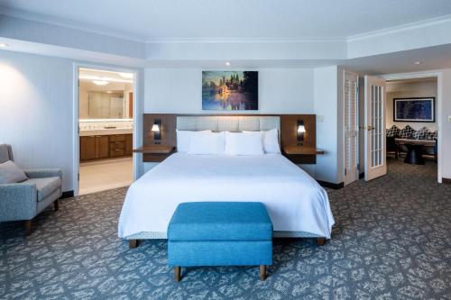a bedroom with a large bed with a blue ottoman at Embassy Suites by Hilton Portland Airport in Portland
