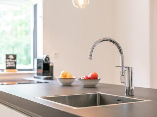 a kitchen counter with a sink and two bowls of fruit at Maison Clement in Maasmechelen