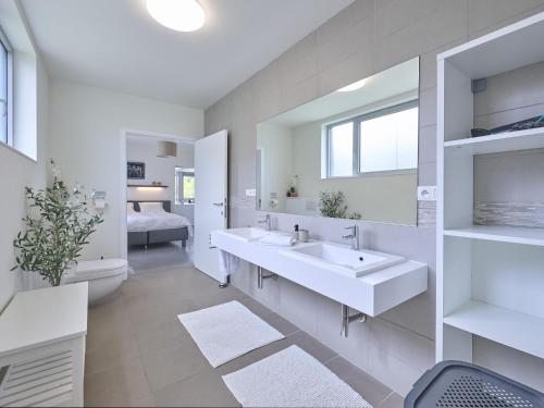 a white bathroom with two sinks and a bedroom at Maison Oscar in Tongeren