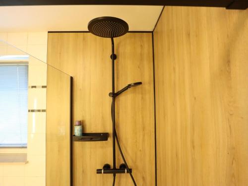 a shower in a bathroom with a wooden wall at Villa Belvedère in Houffalize