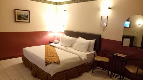 a hotel room with a large bed and a chair at DM Residente Hotel Inns & Villas in Angeles