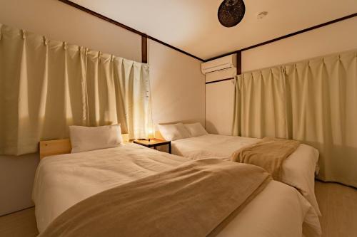 two beds in a room with white sheets at Tsuga1976 in Chiba