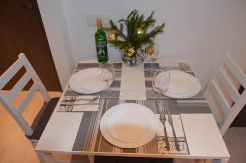 a table with two white plates and a bottle of wine at Apartments Ozo Park in Vilnius