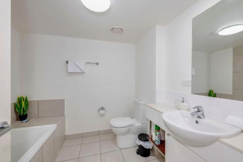 a white bathroom with a sink and a toilet at Dwell Apartment 33 in Bargara