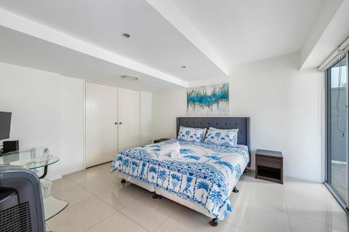 a bedroom with a bed with a blue and white comforter at Dwell Apartment 33 in Bargara