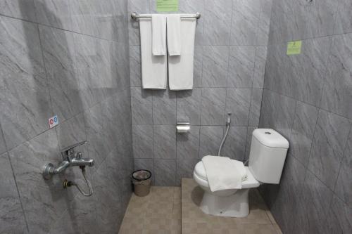 a bathroom with a toilet and towels on the wall at Yasminstar Hotel in Muntok