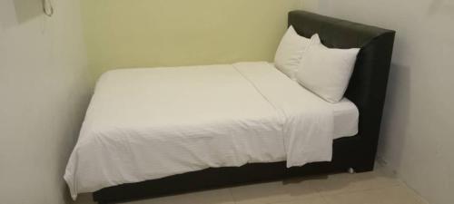 a small bed with white sheets and a black headboard at Elite Hotel in Kuantan