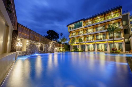 a swimming pool in front of a building at night at Aqua Resort SHA Plus in Rawai Beach