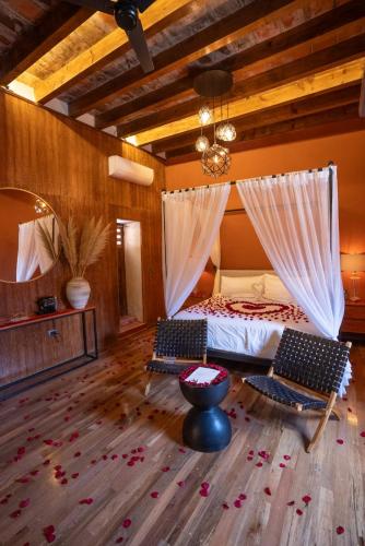 a bedroom with a bed with two chairs and a mirror at Hotel Bitos Boutique in San Miguel de Allende