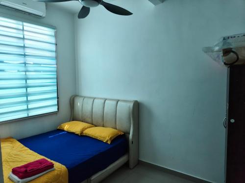 a bedroom with a bed with yellow pillows and a ceiling at Atabara ECRL Stay Homestay in Kuantan