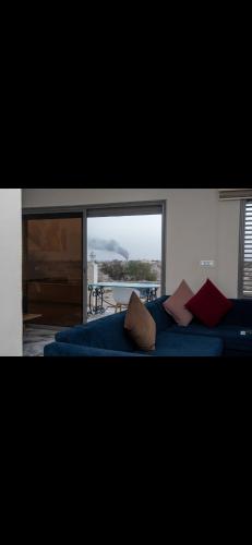 a living room with a blue couch and a large window at Le mirage in Tozeur