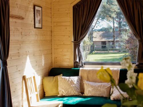 a living room with a green couch and a window at Vilasini Hut by Tiny Away in Great Horkesley