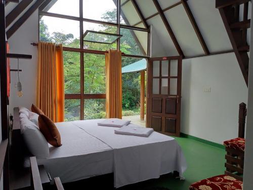 a bedroom with a bed and a large window at Rainforest Tea Garden Cabin-River View in Deniyaya