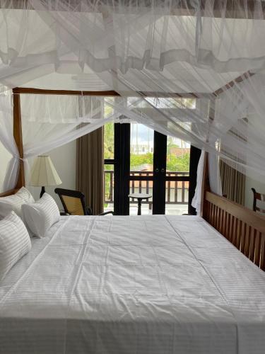 a bedroom with a large bed with a white canopy at Ocean Crest Apartments in Mihiripenne