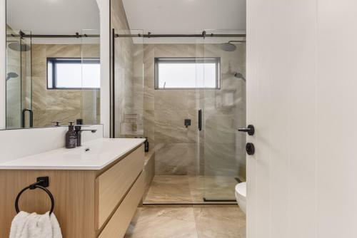 a bathroom with a shower and a white sink at Roam Taupo Lakefront Combined Units 1&2 in Taupo