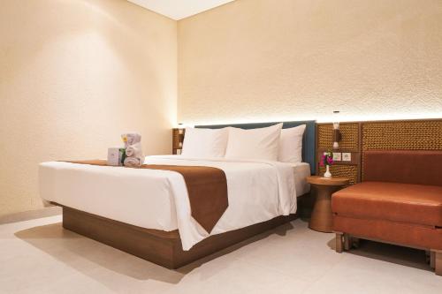 a bedroom with a large bed and a chair at Grand Luxcamp Pangandaran by Horison in Pangandaran