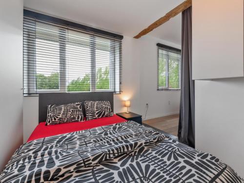 a bedroom with a black and white bed and windows at Landhuis Brakelbos in Brakel