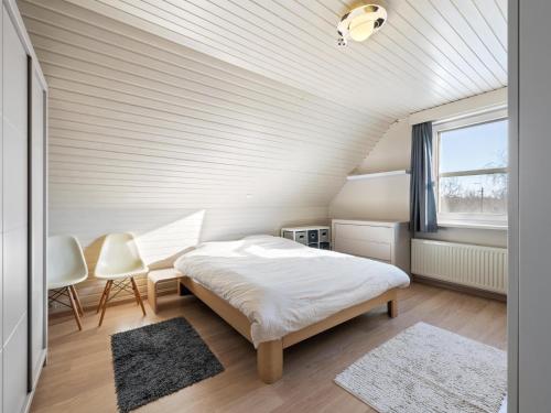 a bedroom with a bed and two chairs and a window at Maison Odille in Sint-Laureins