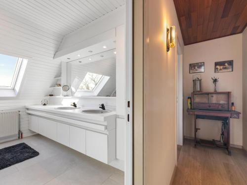 a white bathroom with a sink and a mirror at Maison Odille in Sint-Laureins