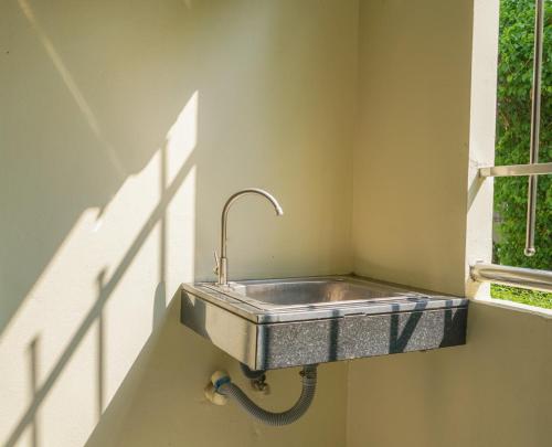 a sink in the corner of a room with a window at Prukpibul Apartment in Bangkok