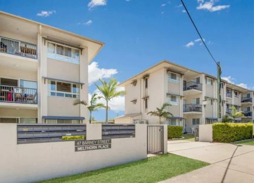 a building with palm trees in front of it at Modern Beach Apartment in Gladstone