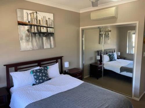 a bedroom with two beds and a large mirror at Modern Beach Apartment in Gladstone
