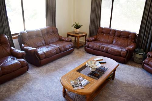 a living room with leather couches and a coffee table at Yarrawonga Holiday House with Open Fireplace in Yarrawonga