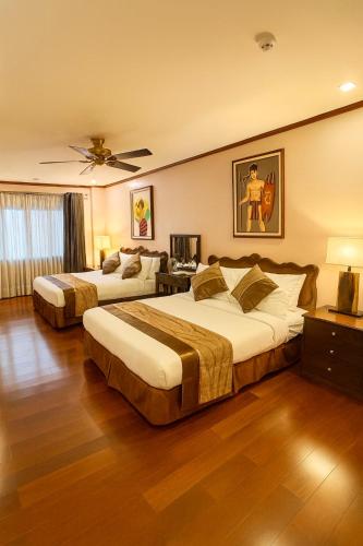 a hotel room with two beds and a ceiling fan at Leonard Wood Pines Hotel in Baguio